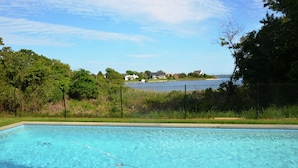 A swimming pool with a view of a lake and houses in the background. - Luxurious Waterfront Retreat in Southampton: Breathtaking Views, Pool, and More! (Southampton)