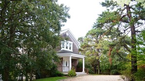 A house with a porch, surrounded by trees and a gravel driveway. - Luxurious Waterfront Retreat in Southampton: Breathtaking Views, Pool, and More! (Southampton)