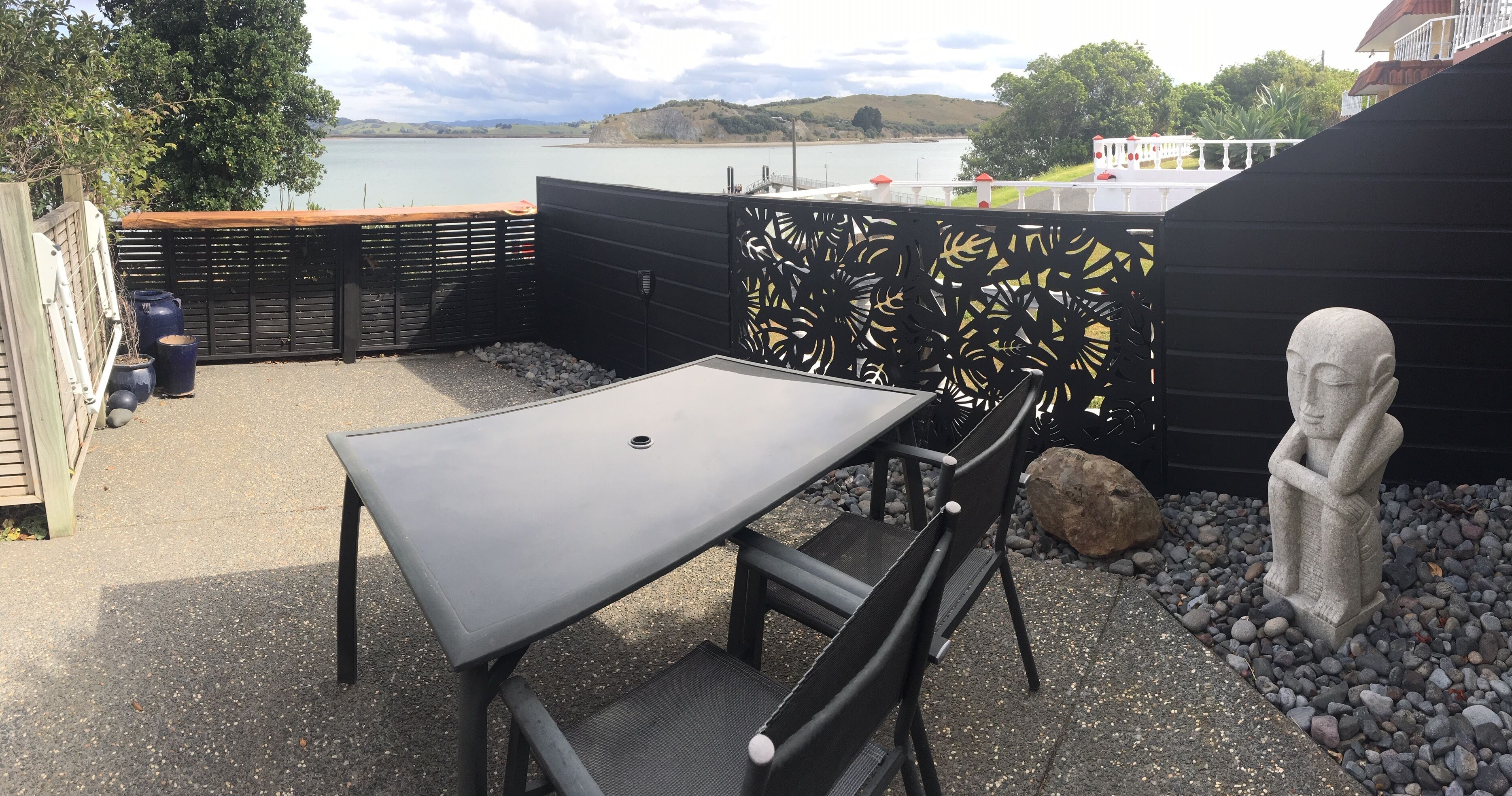 An outdoor seating area with a table and chairs, a decorative fence, and a statue.