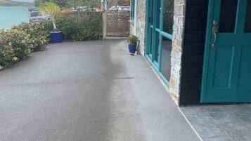 A paved pathway leading to a building with a teal door and stone facade.