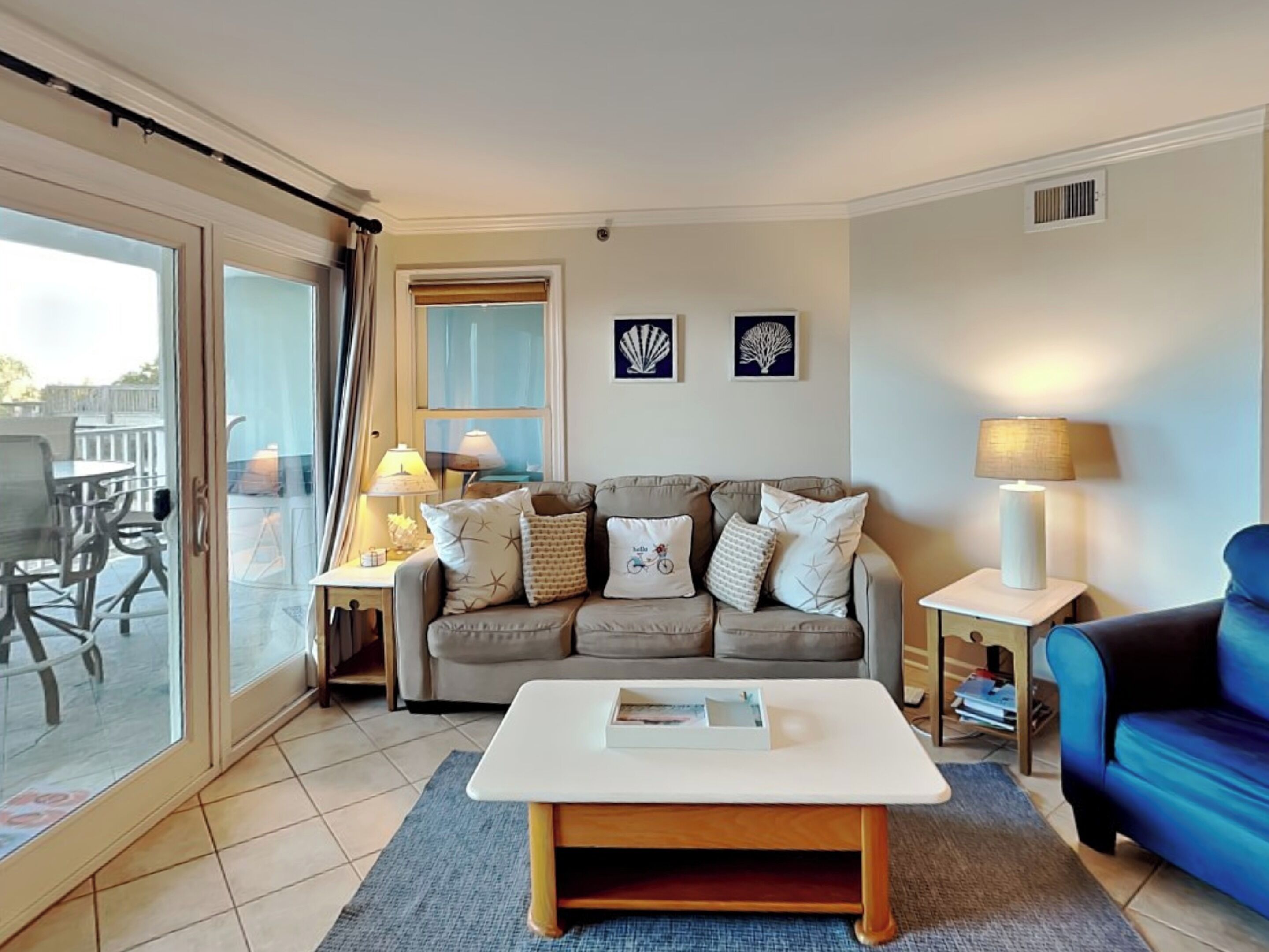 A living room with a sofa, two side tables, a coffee table, and a view through a sliding glass door.