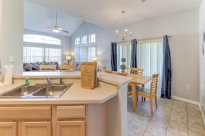 Enjoy meals in the spacious kitchen and dining area, featuring a central island, sink, and wooden table.
