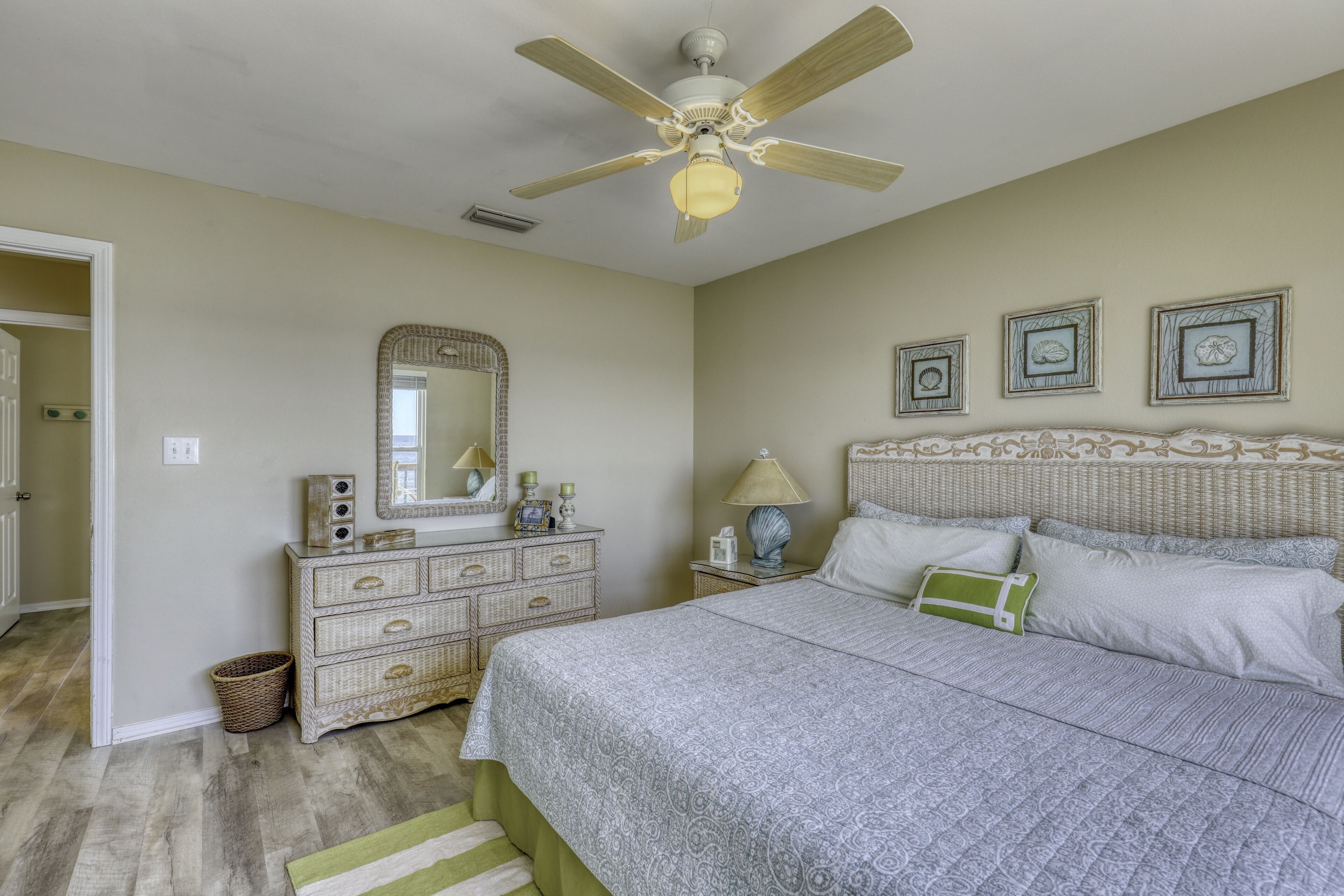 Une chambre à coucher avec un lit, une commode, un miroir et un ventilateur de plafond.
