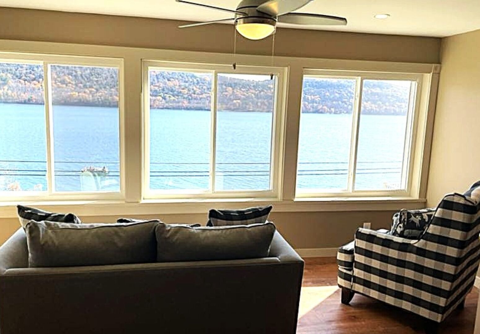 Downstairs enclosed balcony off master BR. Waterfront view. Sofa and arm chair.