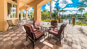 A covered patio with outdoor furniture, a pool, and a view of palm trees and a clear sky. - New Listing! Watersong Resort, 9mi to Disney & 18mi to Universal - FS211222 (Davenport)