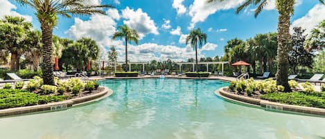 A swimming pool with a 6-inch depth marker, surrounded by palm trees and lounge chairs.