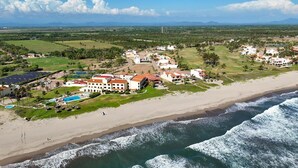 Ein Küstenresort mit mehreren Gebäuden, einem Strand und Blick auf das Meer.