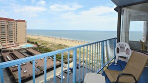 Un balcone con vista su una spiaggia, una piscina e un'area parcheggio.