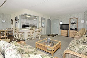 Una sala de estar con sofá, sillas, una mesa de centro y televisor.