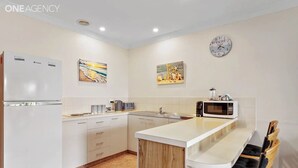 Una cocina moderna con refrigerador, microondas, pileta y taburetes de bar.