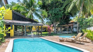 A swimming pool with lounge chairs and a thatched-roof structure.