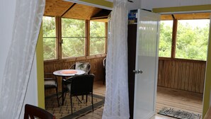A room with a wooden ceiling, a dining table with chairs, a white door, and large windows with a view of trees. - Beautiful,Sandy Beach! 50 steps to the BEACH! Winter dates available book now! (Villa Borquien)