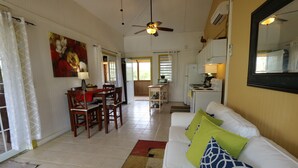 A spacious living area with a white sofa, a dining table with chairs, a kitchen area with a stove and refrigerator, and a ceiling fan. - Beautiful,Sandy Beach! 50 steps to the BEACH! Winter dates available book now! (Villa Borquien)