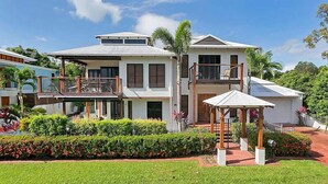 Ein zweistöckiges Haus mit Balkon, überdachter Terrasse und gepflegtem Garten.