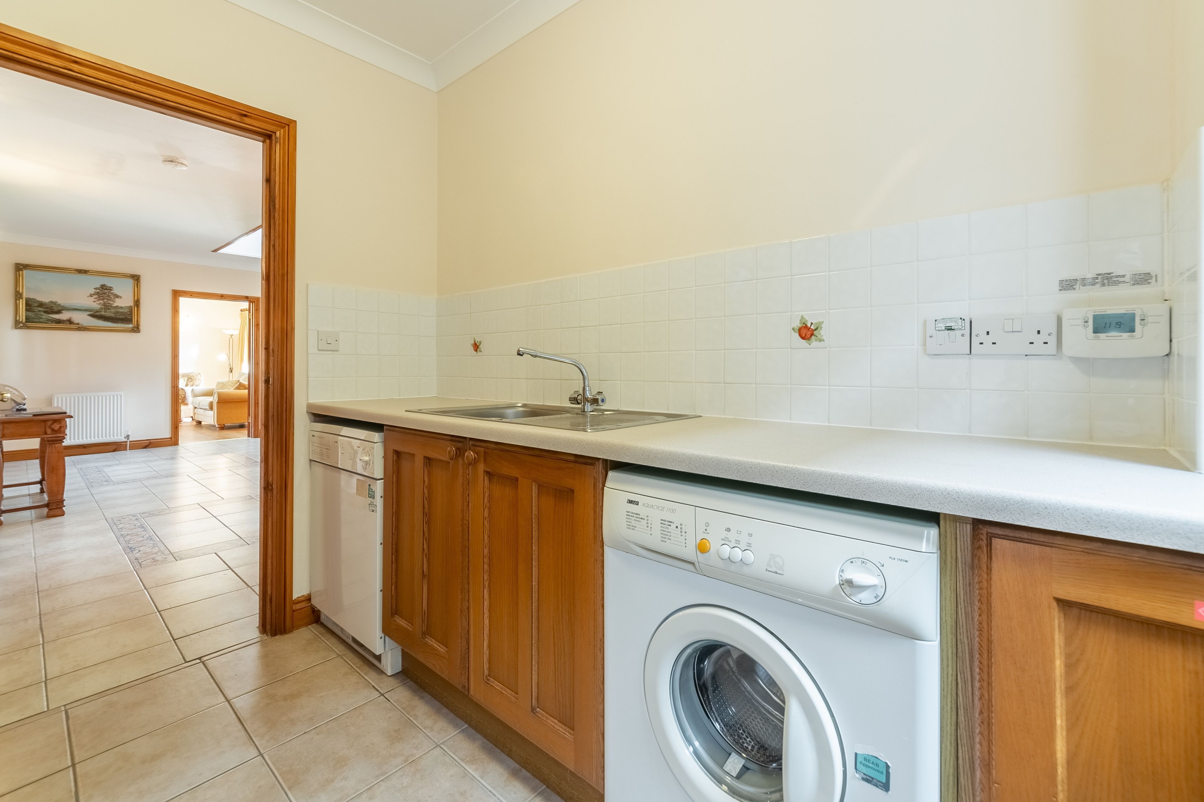 A kitchen with wooden cabinets, a built-in dishwasher, and a countertop with a sink.