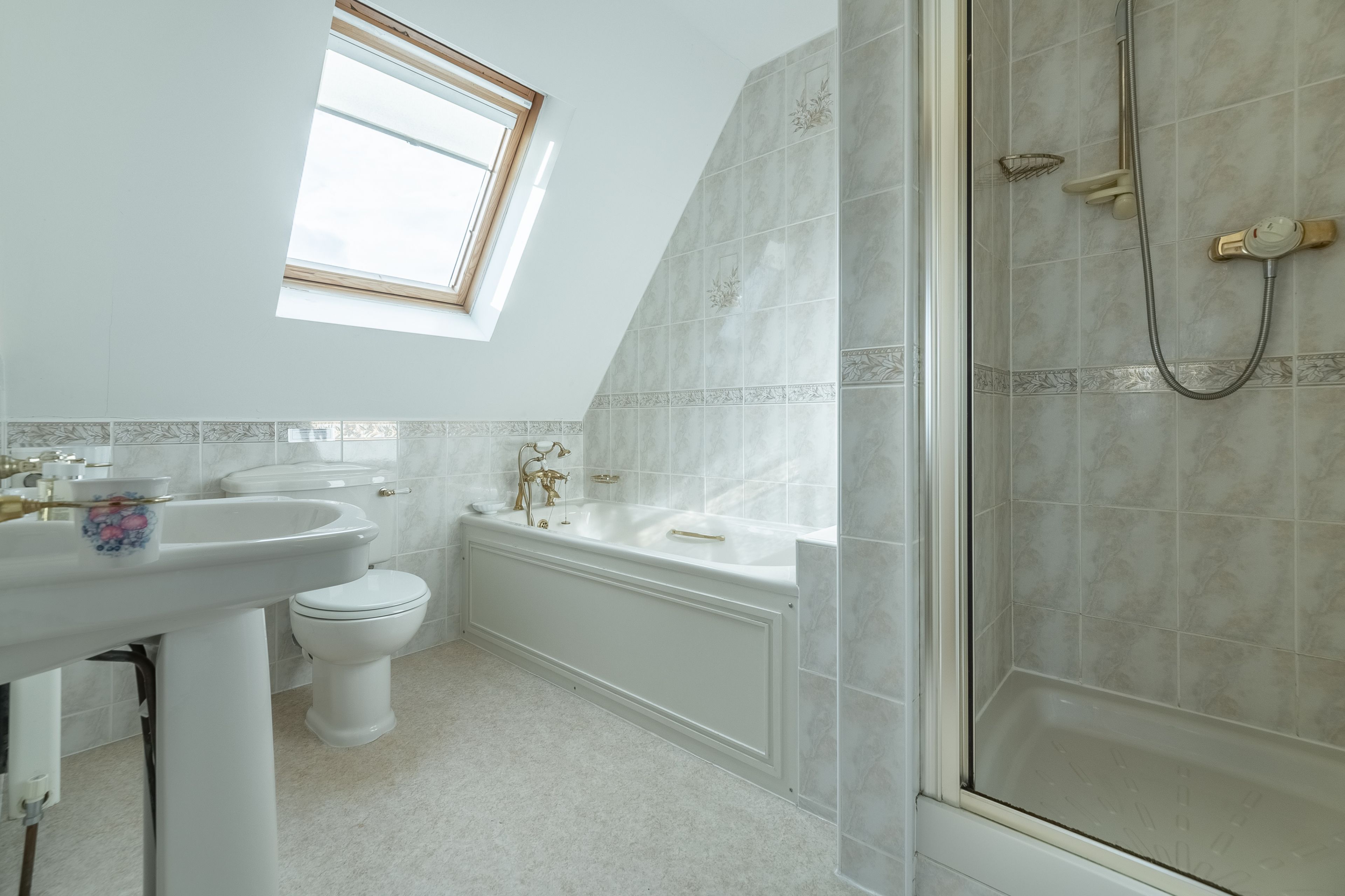 Un bagno con finestra sul tetto, una vasca, un water e una doccia.