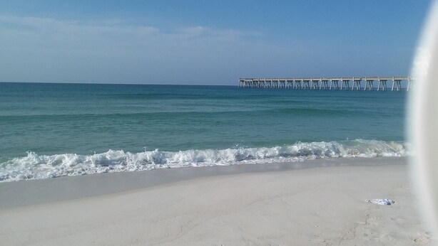 A beach with a pier extending into the ocean. - Beach lover's paradise (Gulf Breeze)