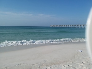 A beach with a pier extending into the ocean.