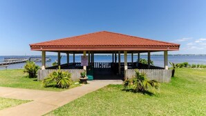 A gazebo with a red roof, located near a body of water with a dock in the background. - Beach lover's paradise (Gulf Breeze)