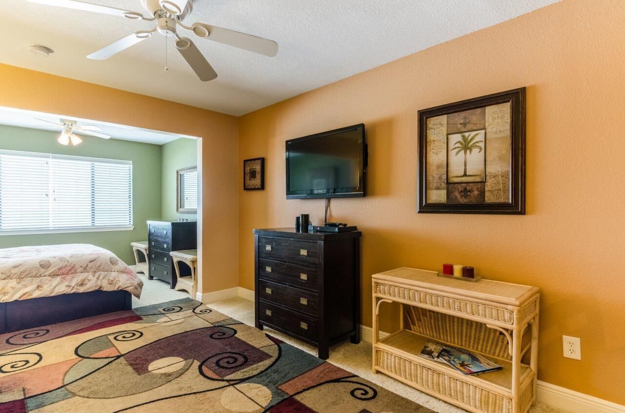 A bedroom with a bed, dresser, television, and a decorative wall piece.