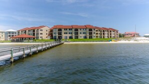 A waterfront hotel with multiple buildings, a dock, and a sandy beach. - Beach lover's paradise (Gulf Breeze)