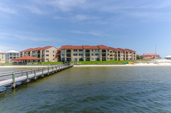 A waterfront hotel with multiple buildings, a dock, and a sandy beach.