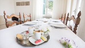A dining table set with plates, glasses, a tray with pastries, and a vase with flowers. - Charming historical 4 guests apartment stunning sea view free wi- fi parking  (Monterosso al Mare)