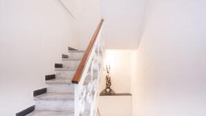 A staircase with marble steps and a wooden handrail, leading to a landing with a wall-mounted clock and a light fixture. - Charming historical 4 guests apartment stunning sea view free wi- fi parking  (Monterosso al Mare)
