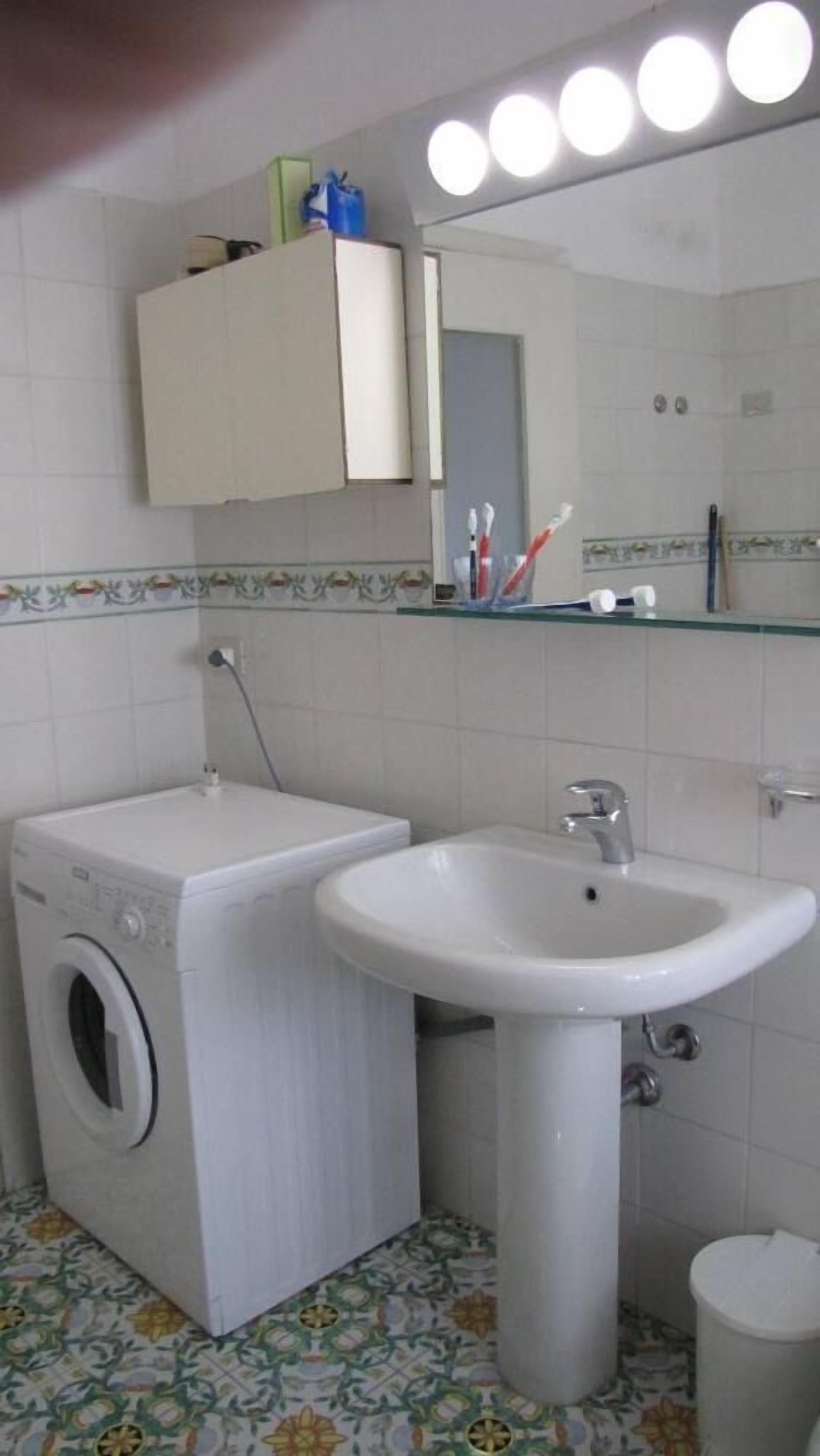 Een kleine badkamer met een wasmachine, een wastafel en een toilet.