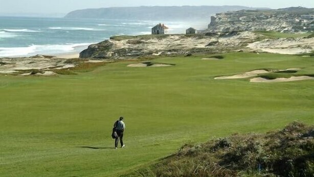 Ein Küsten-Golfplatz mit freiem Blick auf das Meer und felsige Klippen im Hintergrund.