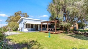 A house with a covered patio, a lawn, and a large tree. - Beach Cottage in the Heart of Mandurah (Mandurah)