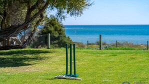 A cricket pitch with stumps and bails on a grassy field with a view of the sea. - Beach Cottage in the Heart of Mandurah (Mandurah)