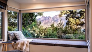 Ein modernes Zimmer mit einem großen Fenster und Blick auf Berge und Grün.