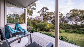 Eine Terrasse mit Sitzgelegenheit, Blick auf eine Berglandschaft und ein Gartenbereich.