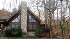 Eine Holzhütte mit Steinofen, Holzfassade und Veranda mit Gittergeländer.