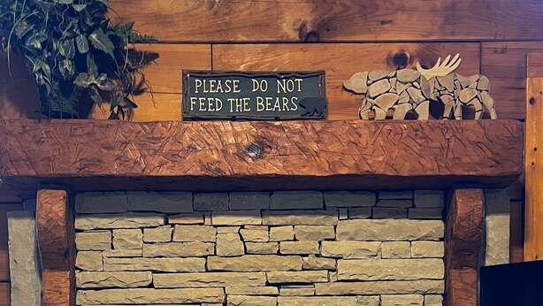 Ein Steinkamin mit einem Schild darüber, auf dem steht: "BITTE NICHT DIE BÄREN FÜTTERN."