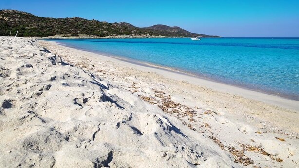A beach with clear turquoise water, white sand, and a boat in the distance. - Quiet 500 m from Lozari beach (Palasca)