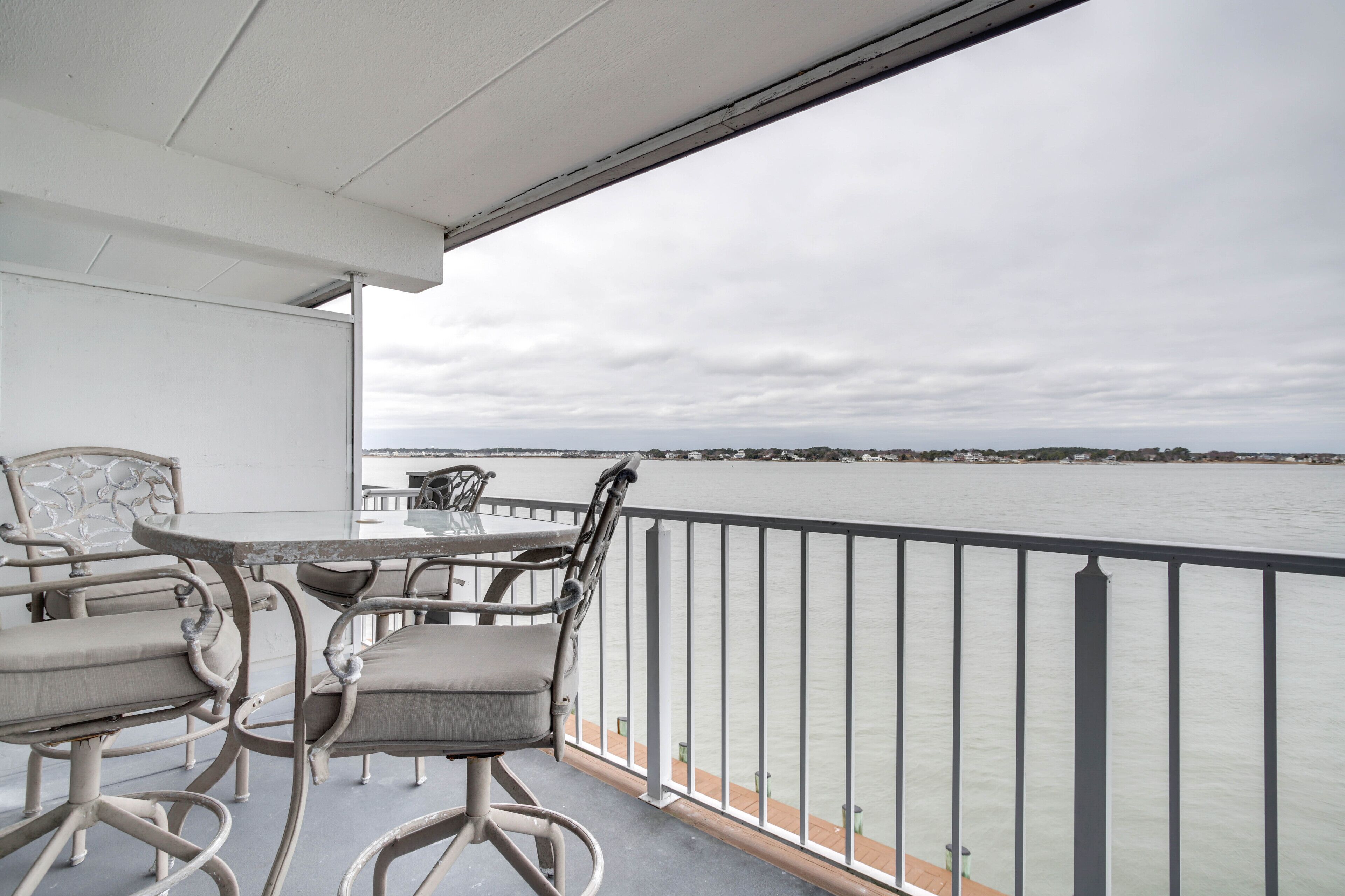 Un balcon avec une table et des chaises donnant sur une étendue d’eau.