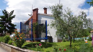 A modern building with a brick chimney, surrounded by a well-maintained garden with various plants and flowers. - Countryside Holiday Apartment In Village Peresiji (Peresiji)