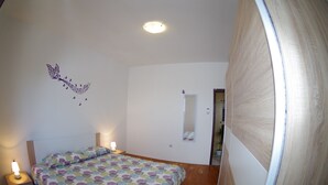 A bedroom with a bed, bedside lamps, a wall decoration, and a mirror. - Countryside Holiday Apartment In Village Peresiji (Peresiji)
