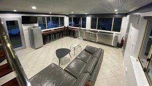 A modern kitchen with a bar area, a sofa, and a dining table. - Hawkesbury River Guest House (Lower Portland)