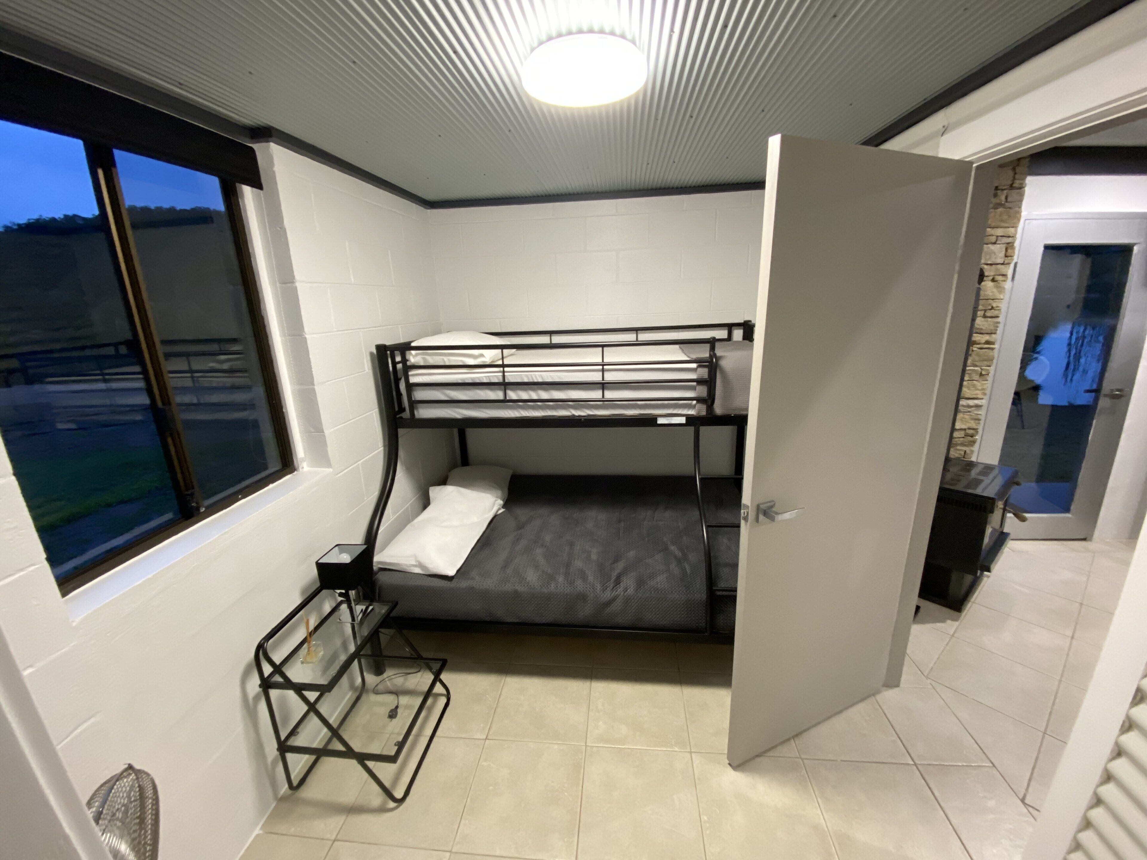 Une petite pièce avec un lit superposé, une petite table et une fenêtre.