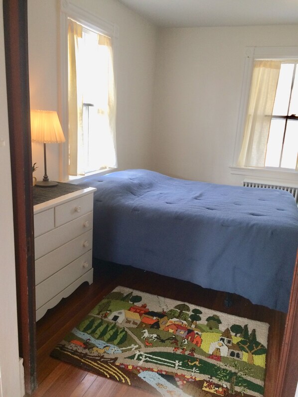 A bedroom with a bed, a dresser, a lamp, and a window with curtains.
