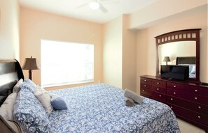 Quarto com cama, cômoda, televisão e ventilador de teto.
