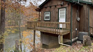 A wooden cabin with a balcony overlooking a lake, surrounded by trees. - Bear Lair: Luxe cabin, private lake, caves, trails, fast WiFi @ Bear Track Lake (Beattyville)