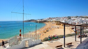Un paysage urbain côtier avec une plage, une promenade et un phare.