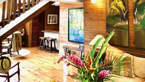 Un vaste espace de vie avec un intérieur en bois, un escalier, un tableau représentant un arbre et un chien.