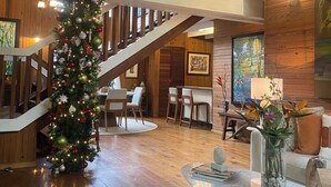 Un hall d’entrée spacieux, agrémenté d’un grand sapin de Noël, d’un plancher en bois, d’un escalier et d’un coin repas.