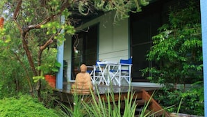 A serene outdoor area with a statue, a covered seating area, and lush greenery.