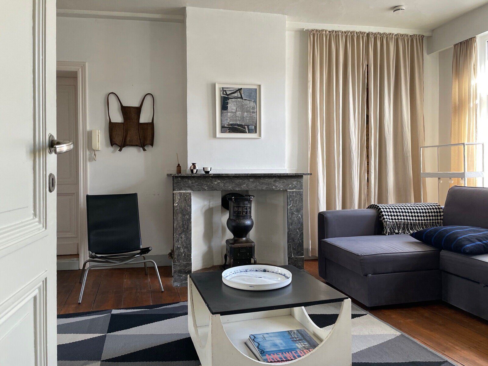 A living room with a sofa, a coffee table, a fireplace, and a door.